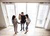 a couple and their baby look at a place with a business woman showing them information